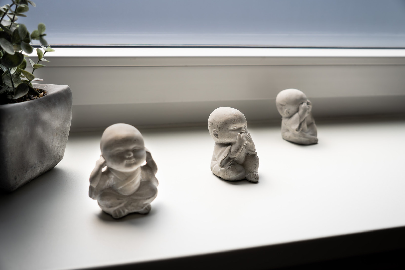Drei kleine Buddha-Figuren als Stillleben auf einer hellen Fensterbank, ruhig und meditativ komponiert.