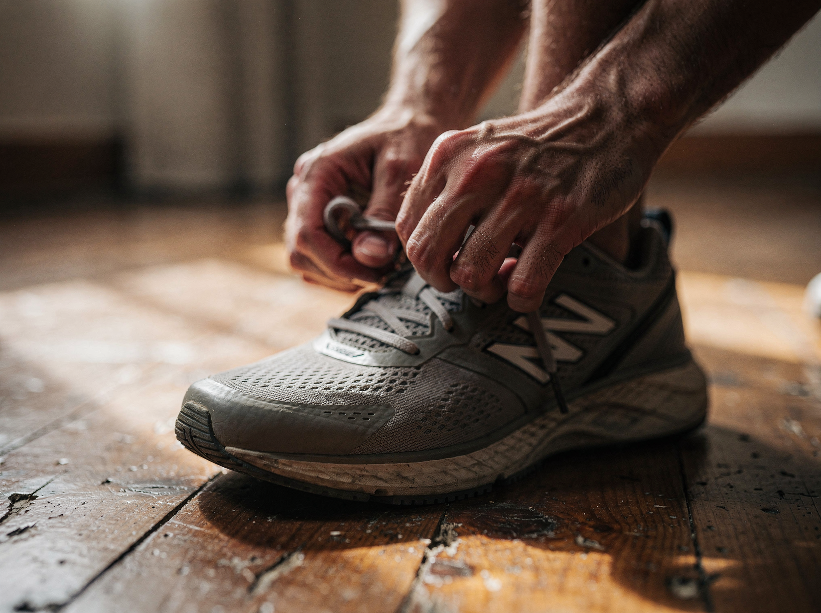 Person bindet im Morgenlicht die Laufschuhe, ruhige Vorbereitung auf Bewegung (KI-generiert)