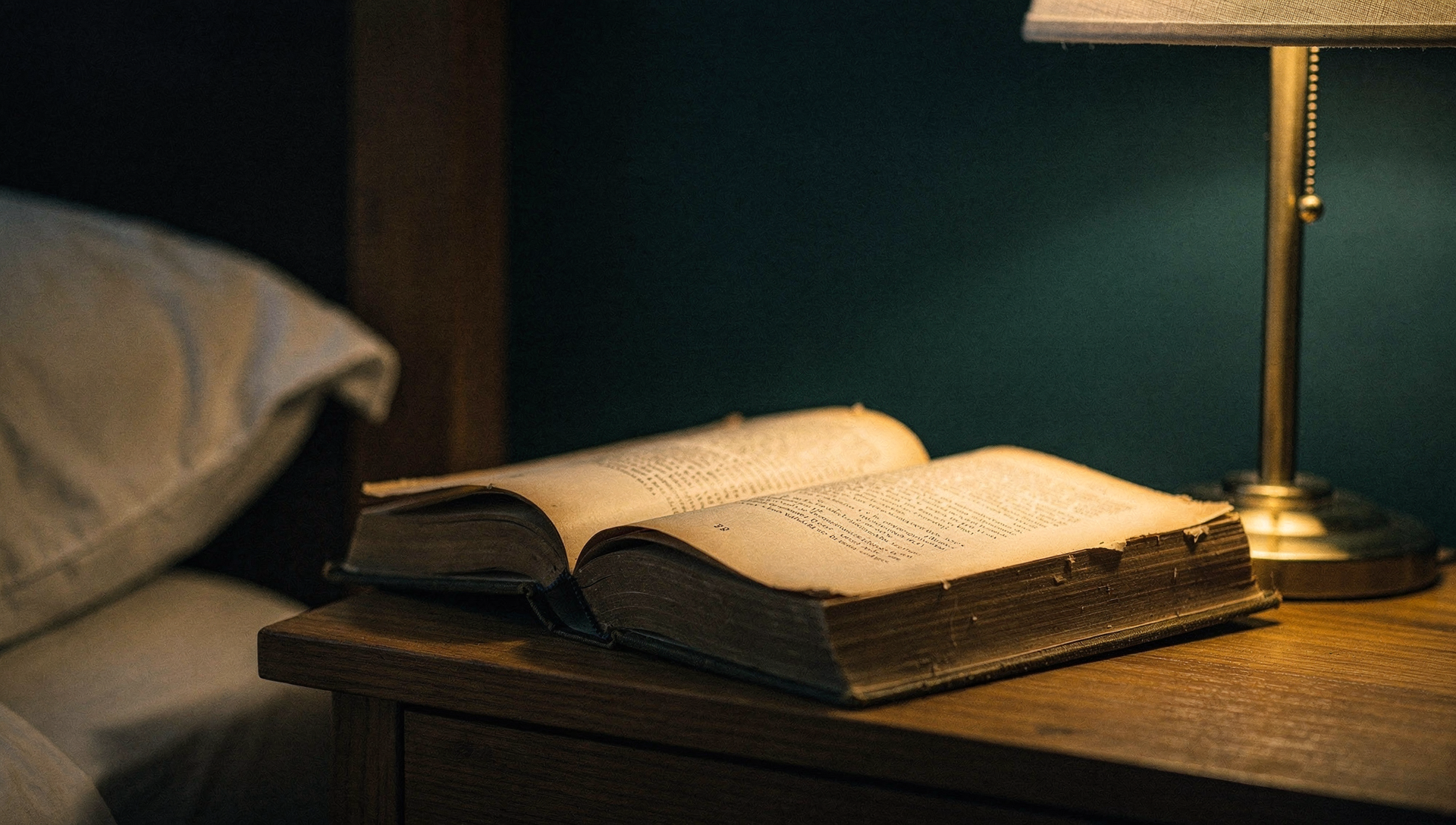 Aufgeschlagenes Buch auf einem Holznachttisch im warmen Schein einer messingfarbenen Leselampe, dunkles Schlafzimmer im Hintergrund, Leinen-Kissen am Rand des Bildes, ruhige Abendstimmung (KI-generiert)